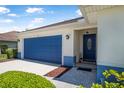 Close-up view of a home's front entrance, showcasing a blue front door, stone walkway, and well-kept landscaping at 43 Pergola Pl, Ormond Beach, FL 32174