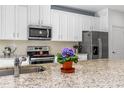 Bright kitchen featuring stainless steel appliances, granite countertops, and white cabinetry at 5635 Estero Loop, Port Orange, FL 32128