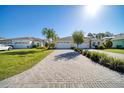 Wide brick driveway leading to a beautiful home with well-manicured lawn and tropical landscaping at 324 Coral Reef Way, Daytona Beach, FL 32124