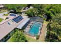 Aerial view showcases a home featuring a screened pool, solar panels, and lush surrounding trees at 75 Knollwood Estates Dr, Ormond Beach, FL 32174