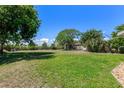 Expansive back yard featuring green grass, chain link fence and mature trees for outdoor enjoyment at 394 Golf Blvd, Daytona Beach, FL 32118