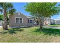 Exterior view of home showing side yard and well-maintained lawn with a mature shade tree at 394 Golf Blvd, Daytona Beach, FL 32118