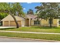 Inviting one-story home with a well-maintained lawn, mature trees, and an attached two-car garage at 518 Moon Rise Dr, Port Orange, FL 32127