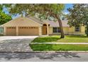 Inviting one-story home featuring a well-kept lawn, two-car garage, and mature shade trees in the front yard at 518 Moon Rise Dr, Port Orange, FL 32127