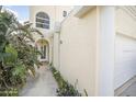 Beautiful side view of the building featuring stucco siding, lush tropical foliage, and a peek at the front door at 3076 Ocean Shore Blvd, Ormond Beach, FL 32176