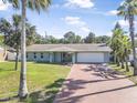 Well-maintained home featuring lush landscaping, a brick driveway, and a two-car garage at 44 Sandra Dr, Ormond Beach, FL 32176