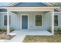 Close up of the front porch of a single-story home with a blue front door at 5620 Ridgewood Ave, De Leon Springs, FL 32130