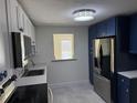 Modern kitchen featuring blue lower cabinets, white upper cabinets, and stainless steel appliances at 127 Mason Park Dr, Daytona Beach, FL 32117
