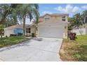 Charming two-story home featuring a two-car garage, well-maintained lawn, and mature palm tree at 1305 Rebecca Dr, Haines City, FL 33844