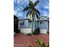 Coastal three-story home with colorful exterior, two-car garage, and lush tropical landscaping at 3000 Ocean Shore Blvd # 150, Ormond Beach, FL 32176