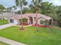 Charming single-story brick home featuring a lush lawn and beautiful palm trees in a tranquil setting at 4622 Secret River Trl, Port Orange, FL 32129