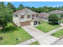 Inviting two-story home featuring a well-kept lawn, driveway and beautiful trees in the background at 5 Cantilever Ct, Ormond Beach, FL 32174