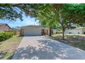 Lovely home featuring an expansive driveway and garage, framed by mature trees and landscaping at 1465 Admrial Nimitz Ave, Daytona Beach, FL 32124
