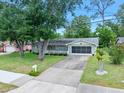 Single-story home featuring a well-maintained lawn, mature trees, driveway, and a screened garage at 241 Sanchez Ave, Ormond Beach, FL 32174