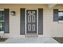 Close up view of the front door featuring gray shutters and stylish exterior lighting at 290 Greenwood Cir, Ormond Beach, FL 32174