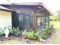 Inviting screened porch featuring comfortable seating, ceiling fans, and views of landscaped flowerbeds at 486 S Us Highway 1, Oak Hill, FL 32759