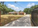 Long concrete driveway leading to a brick home featuring black iron gate entrance and mature landscaping at 5865 Ross Creek Rd, Lakeland, FL 33810