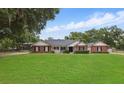Charming single-story brick home with a well-manicured lawn and mature trees at 5865 Ross Creek Rd, Lakeland, FL 33810