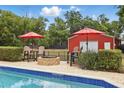 Inviting pool area featuring a brick patio, fire pit, seating area, and a charming red outbuilding at 5865 Ross Creek Rd, Lakeland, FL 33810
