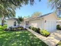 Inviting single-story home with a well-maintained lawn, colorful landscaping, and a two-car garage at 613 Clairmont Ln, South Daytona, FL 32119