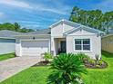 Charming single-story home with a well-manicured lawn, brick driveway, and attached two-car garage at 5539 Estero Loop, Port Orange, FL 32128