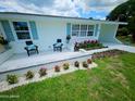 Inviting home exterior with a cozy seating area, vibrant flower beds, and a well-maintained lawn at 68 Hibiscus Dr, Ormond Beach, FL 32176