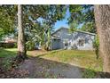 View of the backyard with trees, blue siding on house and green lawn at 1317 Northside Dr, Ormond Beach, FL 32174