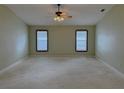 Spacious bedroom with neutral carpet, two windows, and a ceiling fan at 16 Hunt Master Ct, Ormond Beach, FL 32174