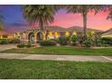 Elegant home featuring a brick driveway, stone entryway, manicured lawn, and beautiful palm trees at sunset at 568 Luna Bella Ln, New Smyrna Beach, FL 32168