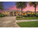 Beautiful single-story home boasting a brick driveway, lush landscaping, and mature palm trees at sunset at 568 Luna Bella Ln, New Smyrna Beach, FL 32168
