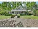Charming single-story home with a welcoming front porch, beautiful landscaping, and an American flag at 3720 Willow Ave, Deland, FL 32720