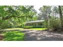 Single-story home with a charming front porch and beautiful landscaping, nestled among mature trees at 3720 Willow Ave, Deland, FL 32720