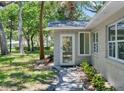 A welcoming entrance with a glass door and a lush green lawn with mature trees at 4901 Sailfish Dr, Ponce Inlet, FL 32127