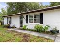 Close-up of a charming home's front entrance with plants, walkway, white brick facade and black shutters at 2101 Almond St, Orange City, FL 32763