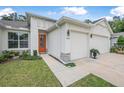 Welcoming home exterior features an orange front door, manicured lawn, and two-car garage at 3029 Adrian Dr, Ormond Beach, FL 32174