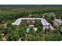 Aerial view of condominium nestled amongst trees featuring a community pool and surrounding landscaping at 640 N Nova Rd # 117, Ormond Beach, FL 32174