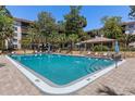 Community swimming pool with lounge seating, tables, and umbrellas, surrounded by landscaped foliage at 640 N Nova Rd # 117, Ormond Beach, FL 32174