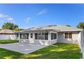 The back exterior of the home showcasing a spacious outdoor patio and lush green lawn for relaxing and entertaining at 807 Scrub Oak St, South Daytona, FL 32119