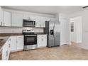 Modern kitchen featuring stainless steel appliances, white cabinetry, and a granite countertop on an easy-to-clean tile floor at 807 Scrub Oak St, South Daytona, FL 32119