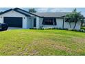 Charming single-story home with a well-manicured lawn, black trim, and a black garage door at 992 Shockney Dr, Ormond Beach, FL 32174