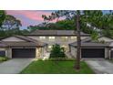 Charming townhome featuring an attached garage, well-maintained lawn, and beautiful landscaping at dusk at 12 Big Buck Trl, Ormond Beach, FL 32174