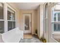 Cozy front porch with white bench seating, tiled floor, and a decorative glass front door at 12 Big Buck Trl, Ormond Beach, FL 32174