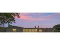 Exterior shot of single-story home at dusk. The facade is lit by interior lights from the large windows at 321 Scotland Dr, Daytona Beach, FL 32117