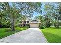 Traditional home boasting a manicured lawn, mature trees, and a two-car garage with brick accents at 1 Crooked Bridge Way, Ormond Beach, FL 32174