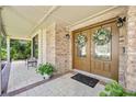 Inviting front porch featuring double doors with glass panels, brickwork, and decorative wreaths at 1 Crooked Bridge Way, Ormond Beach, FL 32174