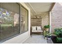 Cozy front porch with brick accent wall, seating area, potted plants, and a view of the outdoors at 1 Crooked Bridge Way, Ormond Beach, FL 32174