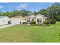 Inviting single-story home featuring a green lawn, flowering shrubs, and an attached two-car garage at 11616 Sw 75Th Cir, Ocala, FL 34476