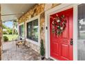 Inviting front porch with a vibrant red door, decorative wreath, and stone detailing at 428 Pelican Bay Dr, Daytona Beach, FL 32119