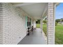 Inviting covered front porch with stylish brick columns and a charming seating area at 999 16Th St, Edgewater, FL 32132