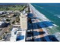 An aerial daytime view of a condo on the beach overlooking the ocean with a pool area between the building and ocean at 89 S Atlantic Ave # 1004, Ormond Beach, FL 32176
